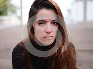 An angry young woman looking hatefully at the camera with an blurred background.