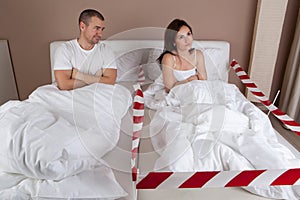 Angry young woman lying separately from husband on the bed