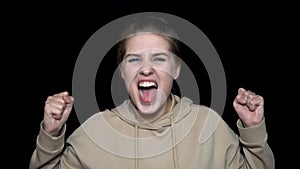 Angry young woman screaming isolated on black background. Enraged female in black background screaming, madness concept