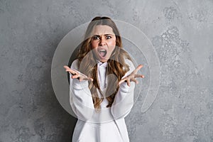 Angry young woman screaming loud while standing