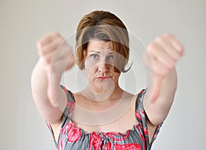 Angry young woman showing thumb down