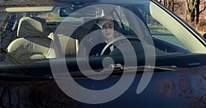 Angry young woman sitting in car and pounding with hands on steering wheel after traffic violation accident while while