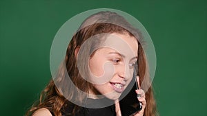 Angry Young woman talking on her cell phone on a green background