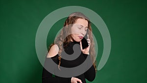 Angry Young woman talking on her cell phone on a green background