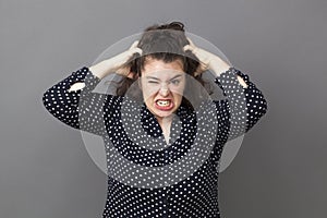 Angry young woman tearing her hair out for stress