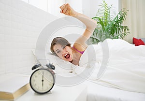 Angry young woman wants to break awakened her alarm clock