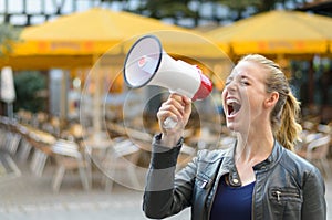 Angry young woman yelling into a megaphone photo