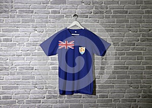 Anguilla flag on shirt and hanging on the wall with brick pattern wallpaper