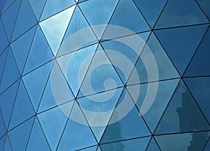 Angular patterned mirrored windows panes reflecting the sky and clouds