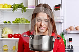 Angy displeased female housewife looks in pot with foul meal, sm