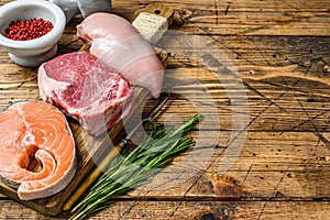 Animal protein sources meat, fish, and poultry. Raw steaks. wooden background. Top view. Copy space