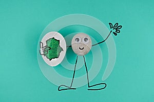 Animated drawing pebble, greeting all and holds one cracked egg with electronic circuit inside, on blue paper background