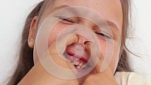 Animated shot of funny, playful, smiling close up cute blond girl with blue eyes picking nose with two hands. Bad habit