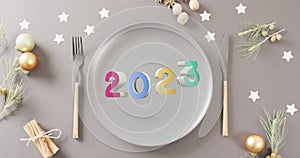 Animation of 2023 text and christmas place setting and decorations in background