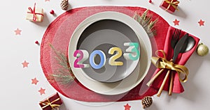 Animation of 2023 text and christmas place setting and decorations in background