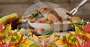 Animation of autumn leaves over thanksgiving dinner background