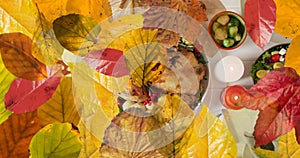 Animation of autumn leaves over thanksgiving dinner background