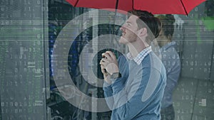 Animation of binary coding and caucasian businessman holding umbrella over server room