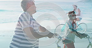 Animation of caucasian girl riding bike over diverse senior couple walking on beach with bike