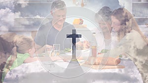 Animation of a Christian cross casting shadow over a Caucasian family praying