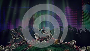Animation of christmas wreath and spotlights over dancing crowd with flashing wall of lights