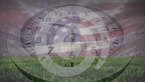 Animation of clock and flag of america over low angle view of grass and empty stadium