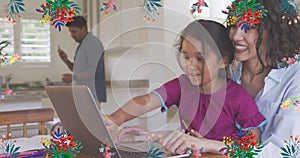 Animation of colourful flowers over smiling mother and daughter using laptop together at home