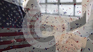 Animation of confetti falling over american flag and businessman handshake