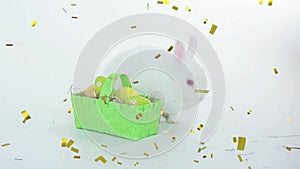 Animation of confetti falling over basket of easter eggs and rabbit on white background