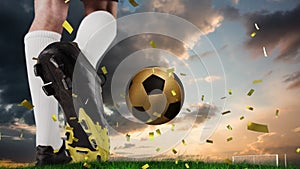 Animation of confetti over feet of caucasian soccer player and gold ball at sunset