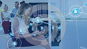 Animation of connected icons over beautiful caucasian woman scrolling on digital tablet in office