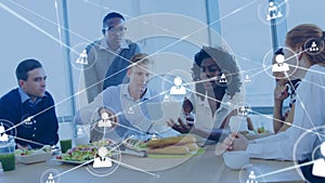 Animation of connected people icons over diverse woman explaining colleagues over tablet at lunch