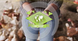 Animation of earthday text over caucasian woman holding seeds with chicken in background