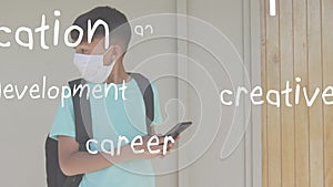 Animation of education words floating boy wearing face mask using a smartphone