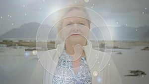 Animation of glowing light over portrait of happy senior woman