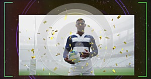 Animation of gold confetti over african american rugby player holding ball in sports stadium