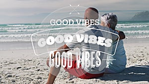 Animation of good vibes text over smiling senior african american couple embracing at beach