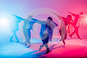 Diverse group of people dancing in studio with red and blue dual color light photo
