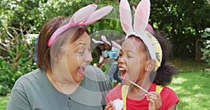 Animation of happy african american grandmother and granddaughter painting easter eggs in garden