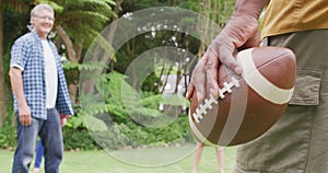 Animation of happy diverse female and male senior friends playing american football in garden