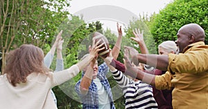 Animation of happy diverse female and male senior friends playing american football in garden