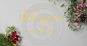 Animation of happy holidays christmas text over decorations on grey background