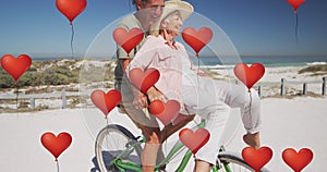 Animation of heart balloon digital icons over senior couple riding bike on beach