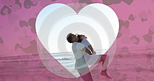 Animation of heart cut out over diverse couple in love on beach in summer