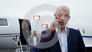 Animation of heart icons over caucasian businessman using smartphone