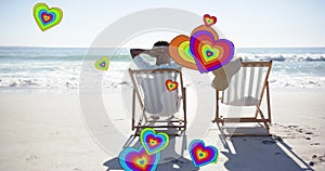 Animation of hearts moving over diverse couple in love in deckchairs on beach in summer