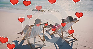 Animation of hearts moving over diverse couple in love in deckchairs on beach in summer