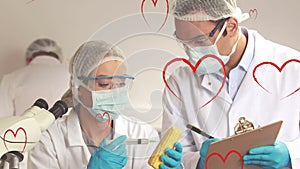 Animation of hearts over caucasian female and male lab workers in safety clothes