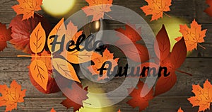 Animation of hellow autumn text over cutlery and autumn leaves over wooden background