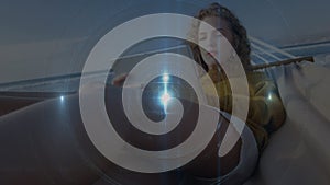 Animation of light beam with circle over caucasian woman using digital tablet on hammock at beach